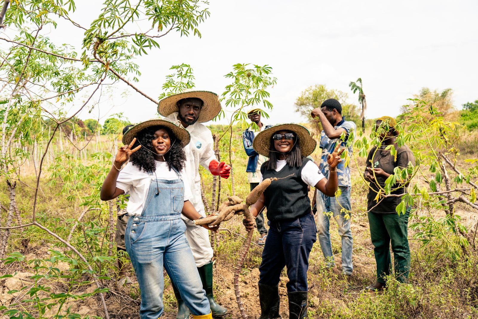 A group of farmers in sun hats standing together in a field, smiling and gesturing